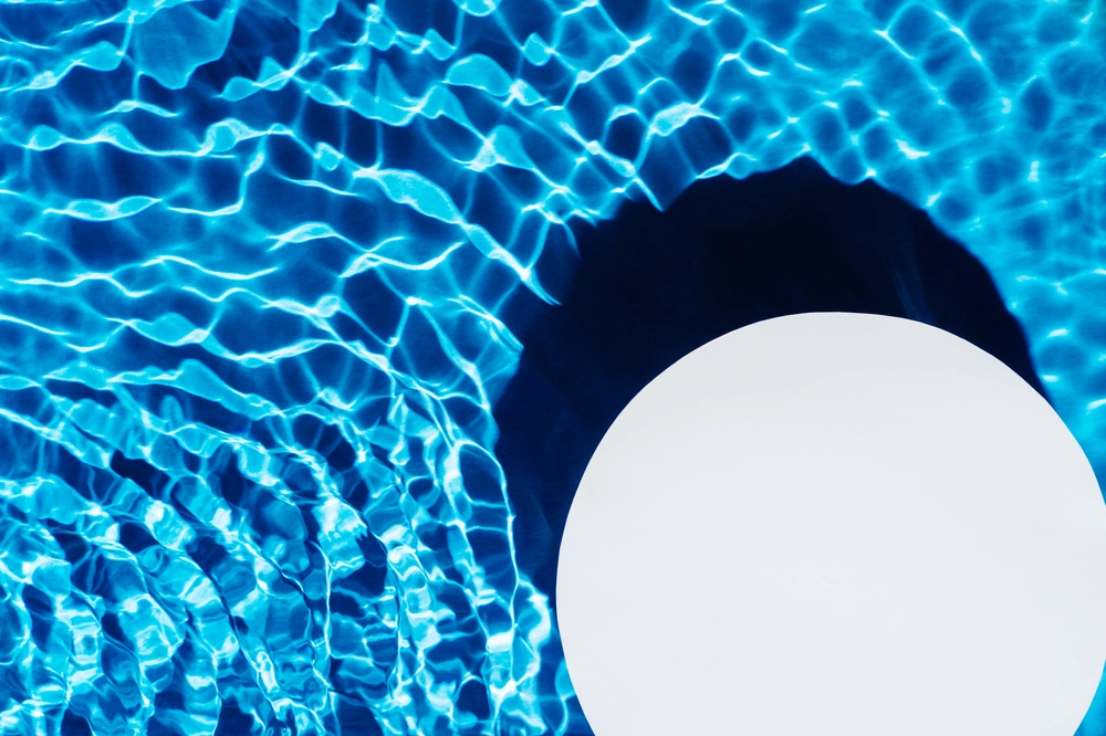 Pływająca okrągła lampa LED na tle jasnoniebieskiej wody basenowej